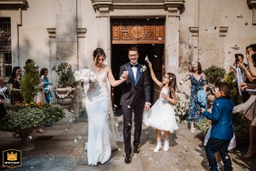 Just-married couple in wedding attire exiting the ceremony location in Turin, Italy.